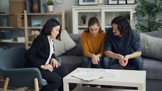 three people sitting on a couch in a living room