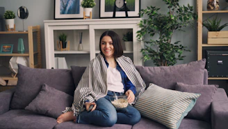 a woman sitting on a couch holding a bowl of popcorn