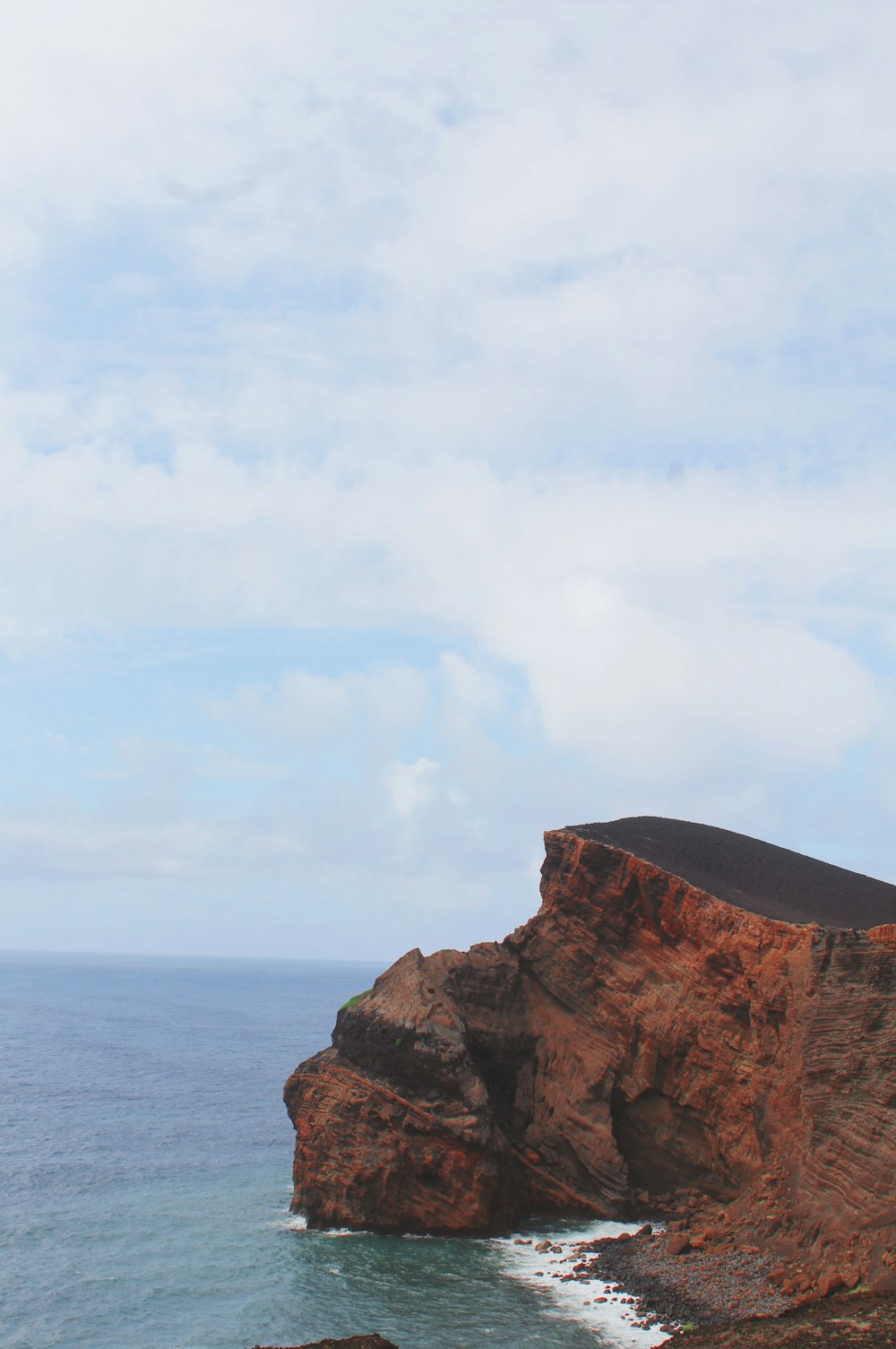 a man standing on top of a cliff next to the ocean