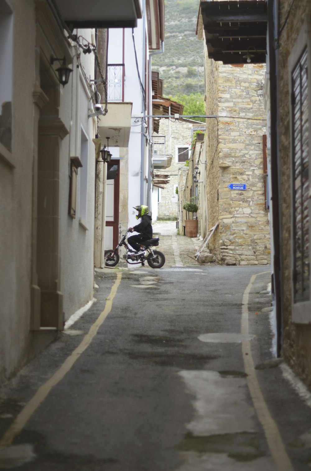 a person riding a motorcycle down a narrow street