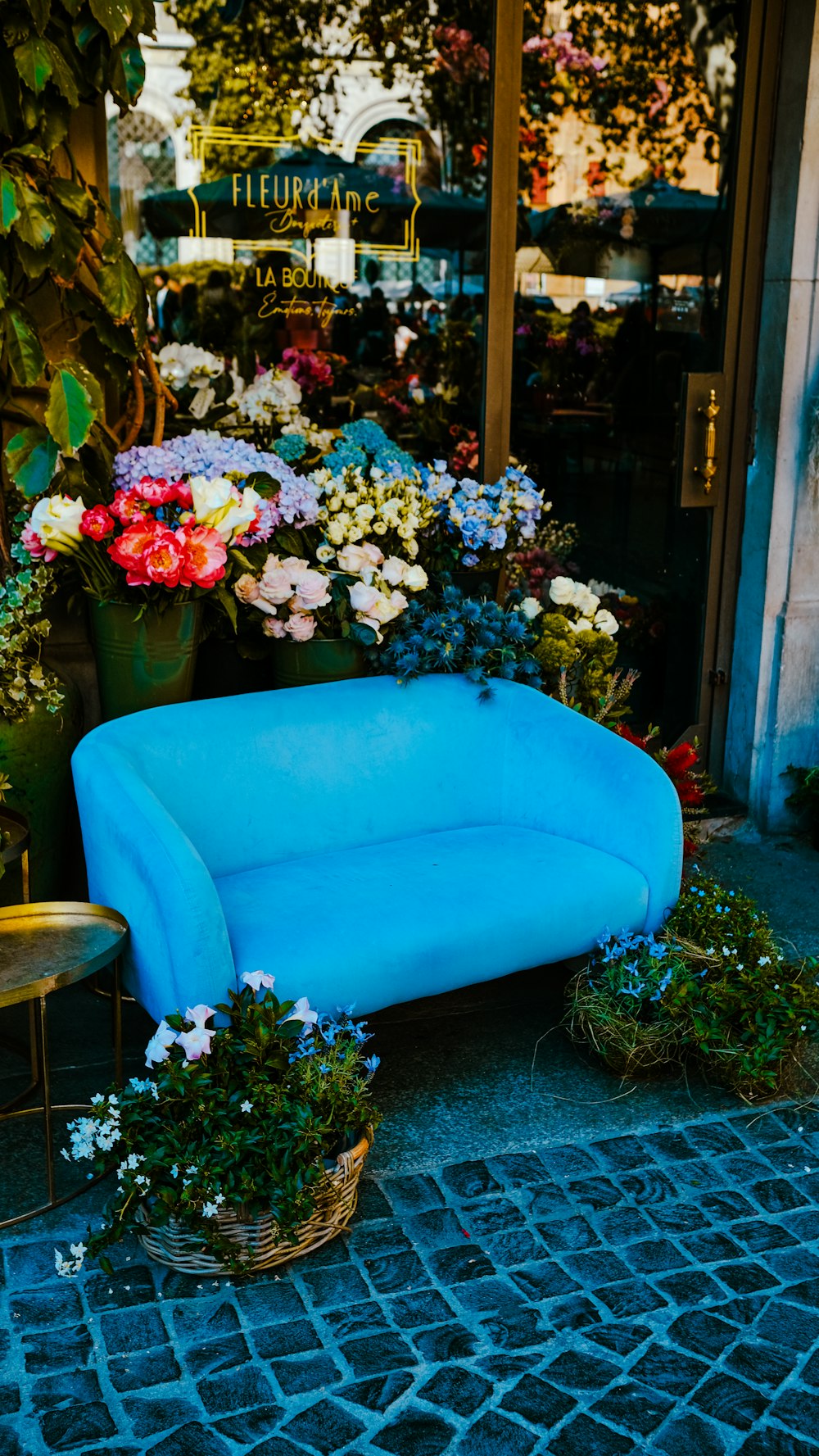 a blue couch sitting in front of a flower shop