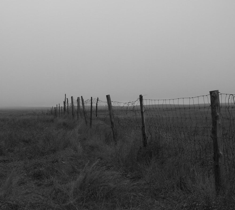 a black and white photo of a fence in a field