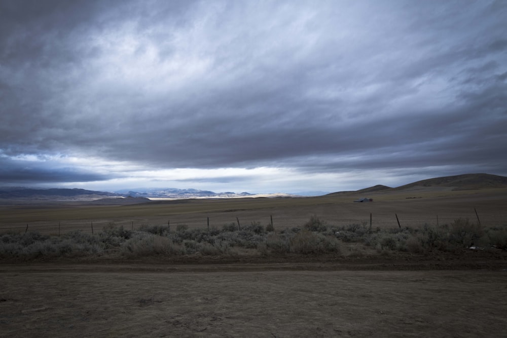 a field with a fence and mountains in the background