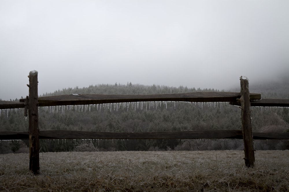 a wooden fence in front of a foggy forest