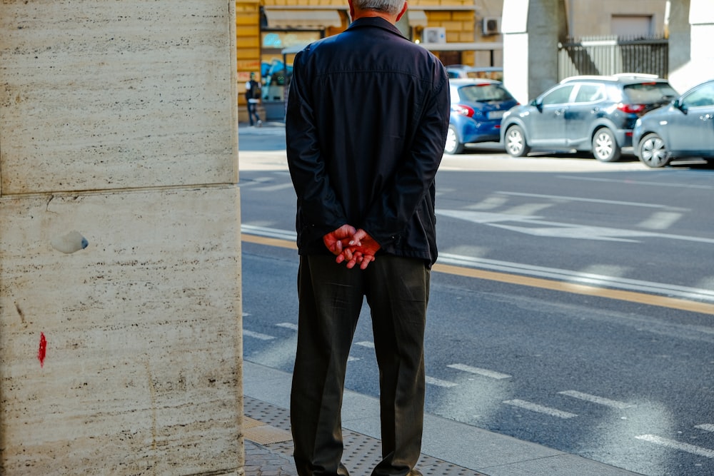 a man standing on a sidewalk with his hands in his pockets