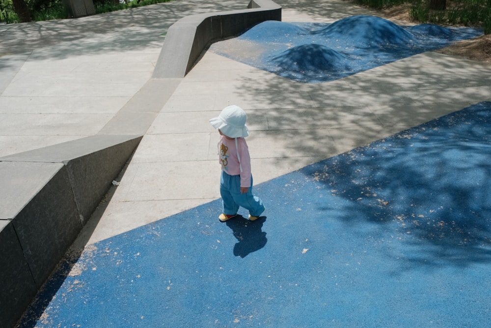 a little girl in a white hat and blue pants