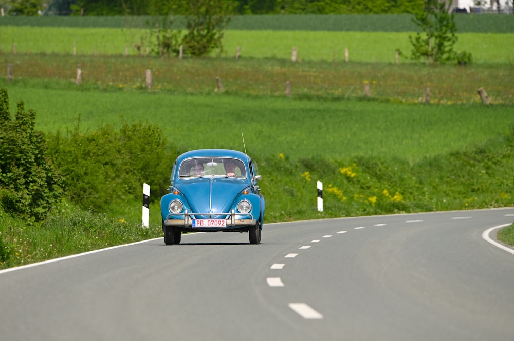 a blue car driving down a country road