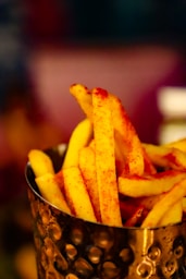 a metal cup filled with french fries on top of a table