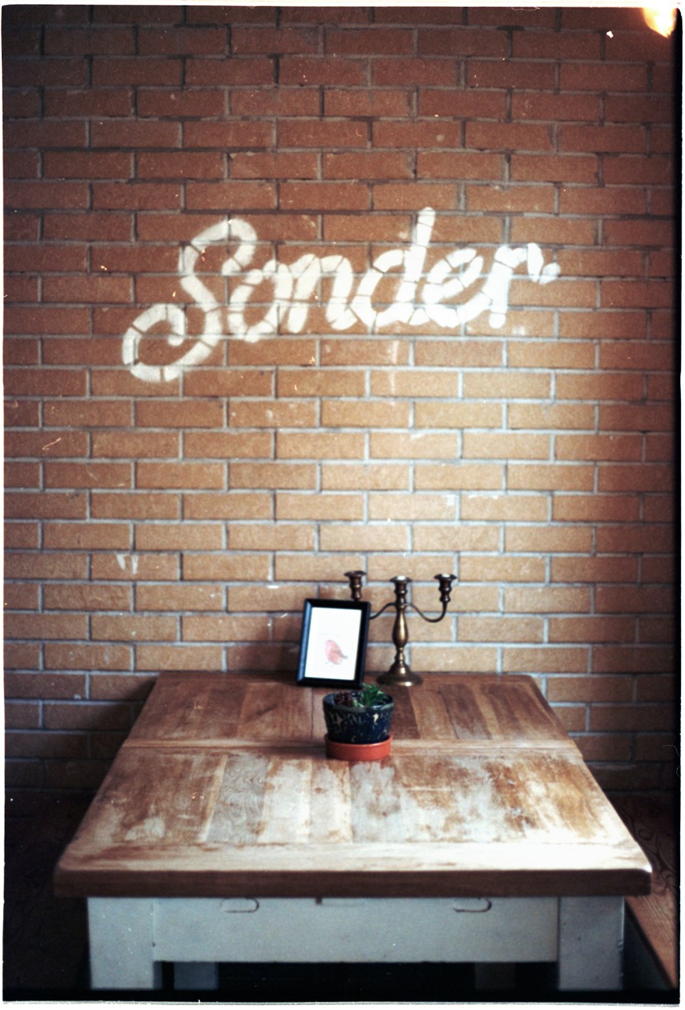 a wooden table sitting in front of a brick wall