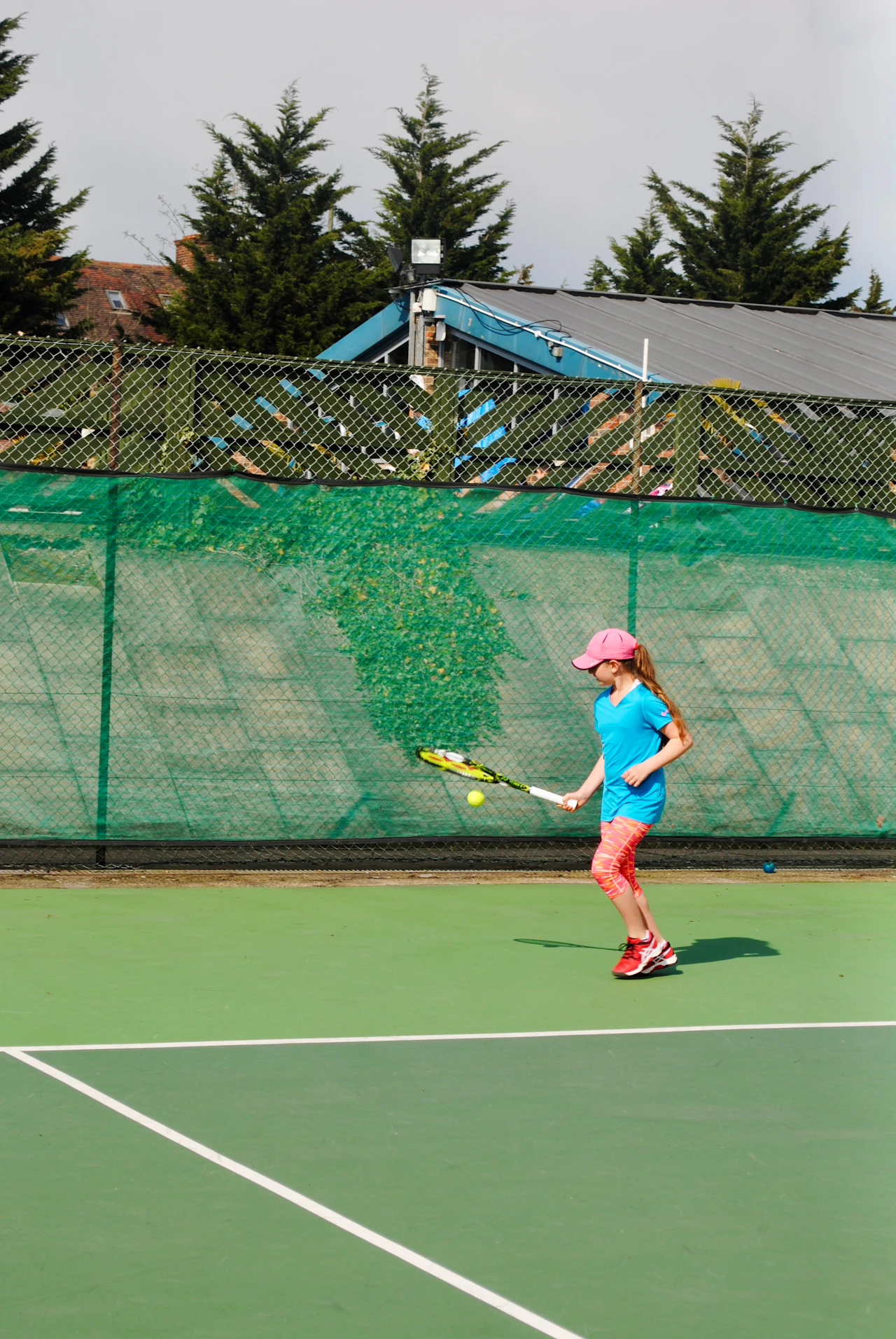 Em bé gái cầm vợt tennis trên sân