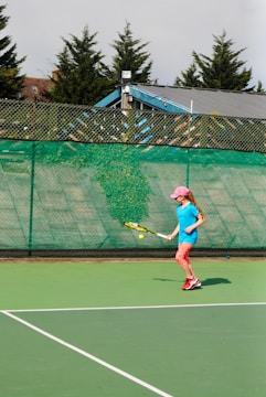 a young girl playing tennis on a tennis court