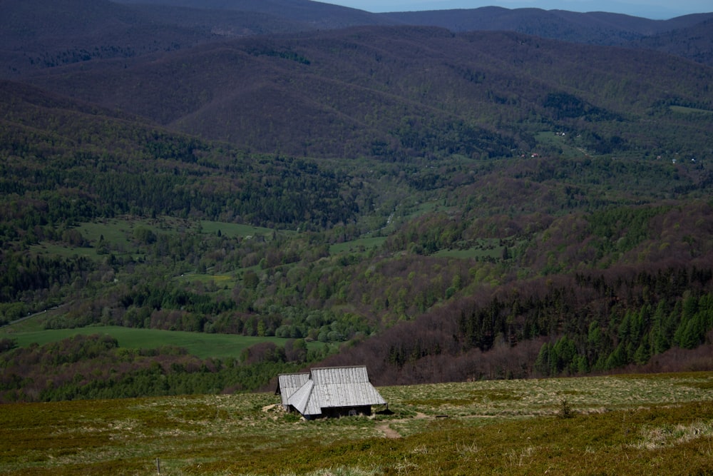 a house in the middle of a field with mountains in the background