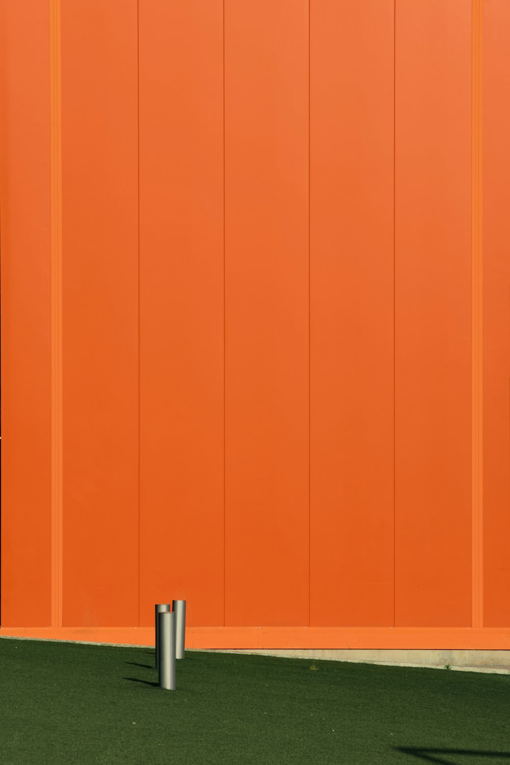 an orange wall with a metal pole in front of it
