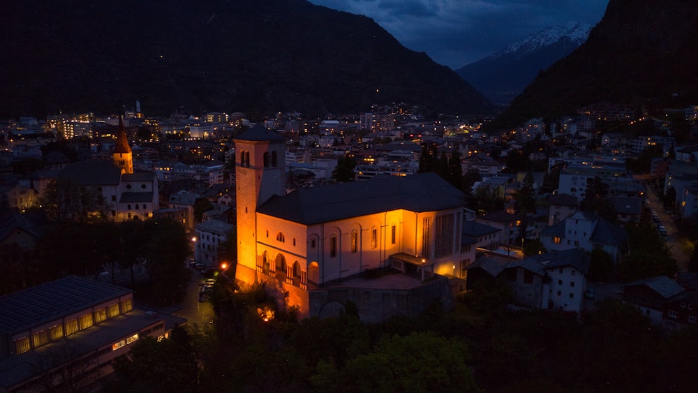 eine große, nachts beleuchtete Kirche mit Bergen im Hintergrund