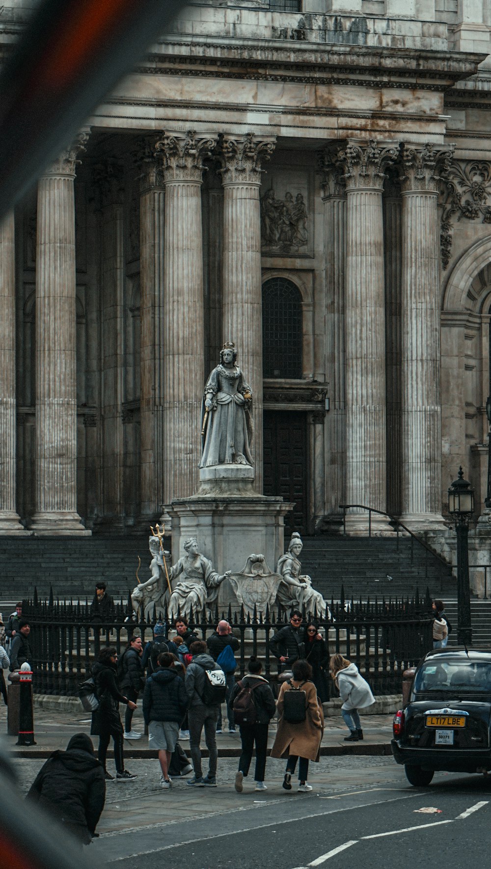 a crowd of people walking across a street next to a tall building