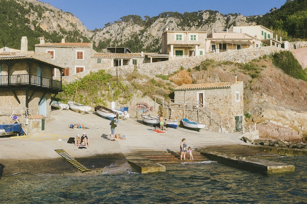 a group of people sitting on a beach next to a body of water