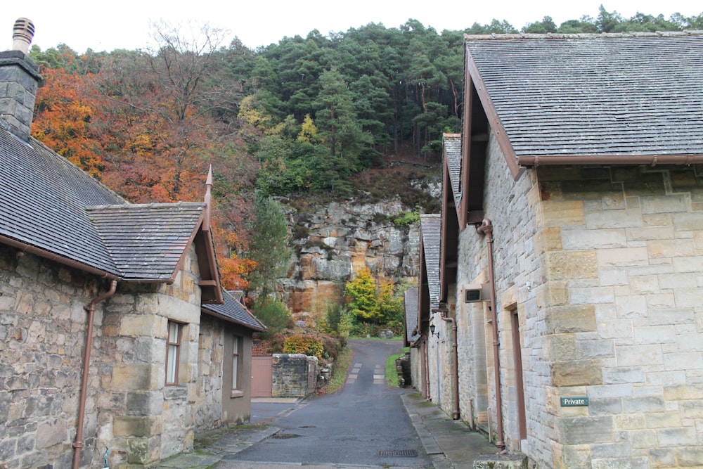 a narrow road between two stone buildings with a steep cliff in the background