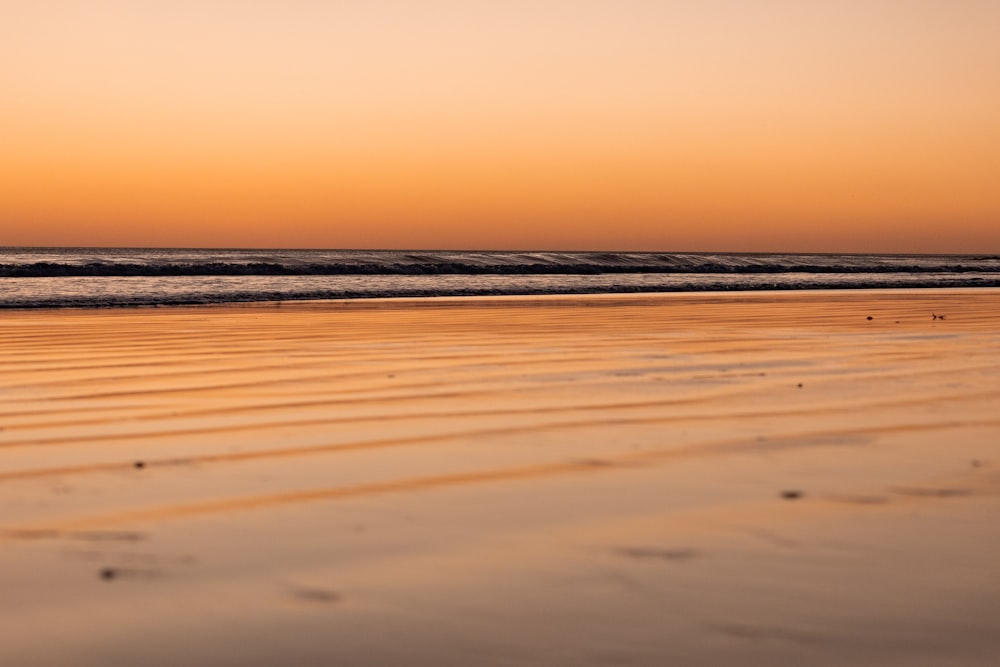 a person walking on a beach at sunset