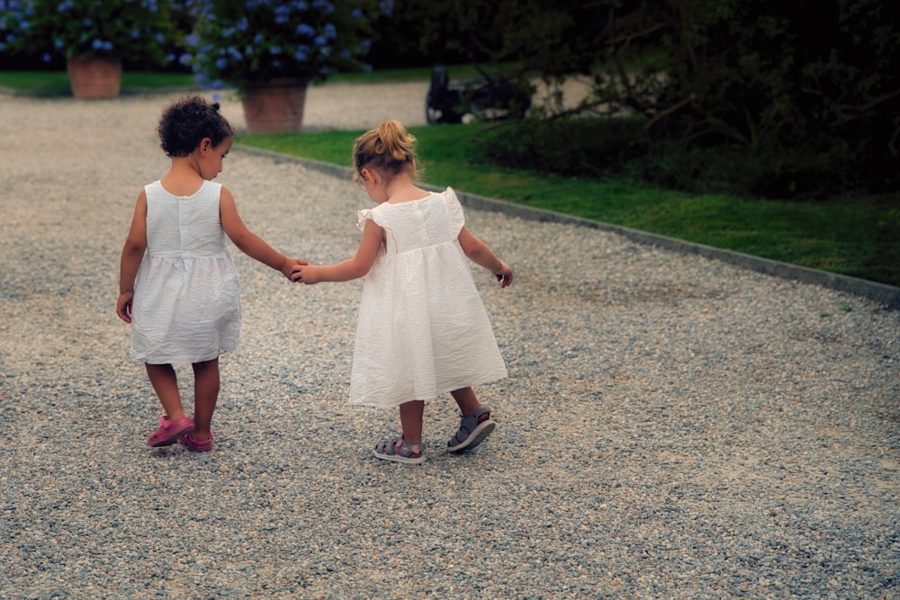 two little girls holding hands in a gravel path