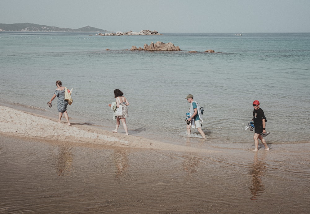 a group of people walking along a beach next to the ocean