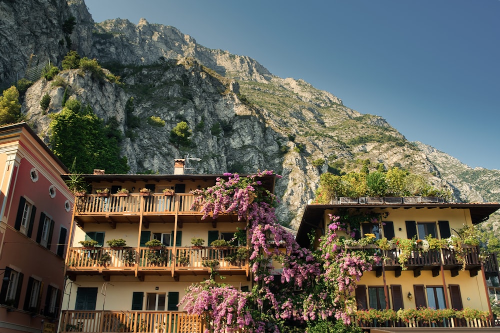 a building with balconies and flowers in front of a mountain