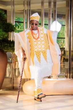 a man in a white and yellow outfit with a cane