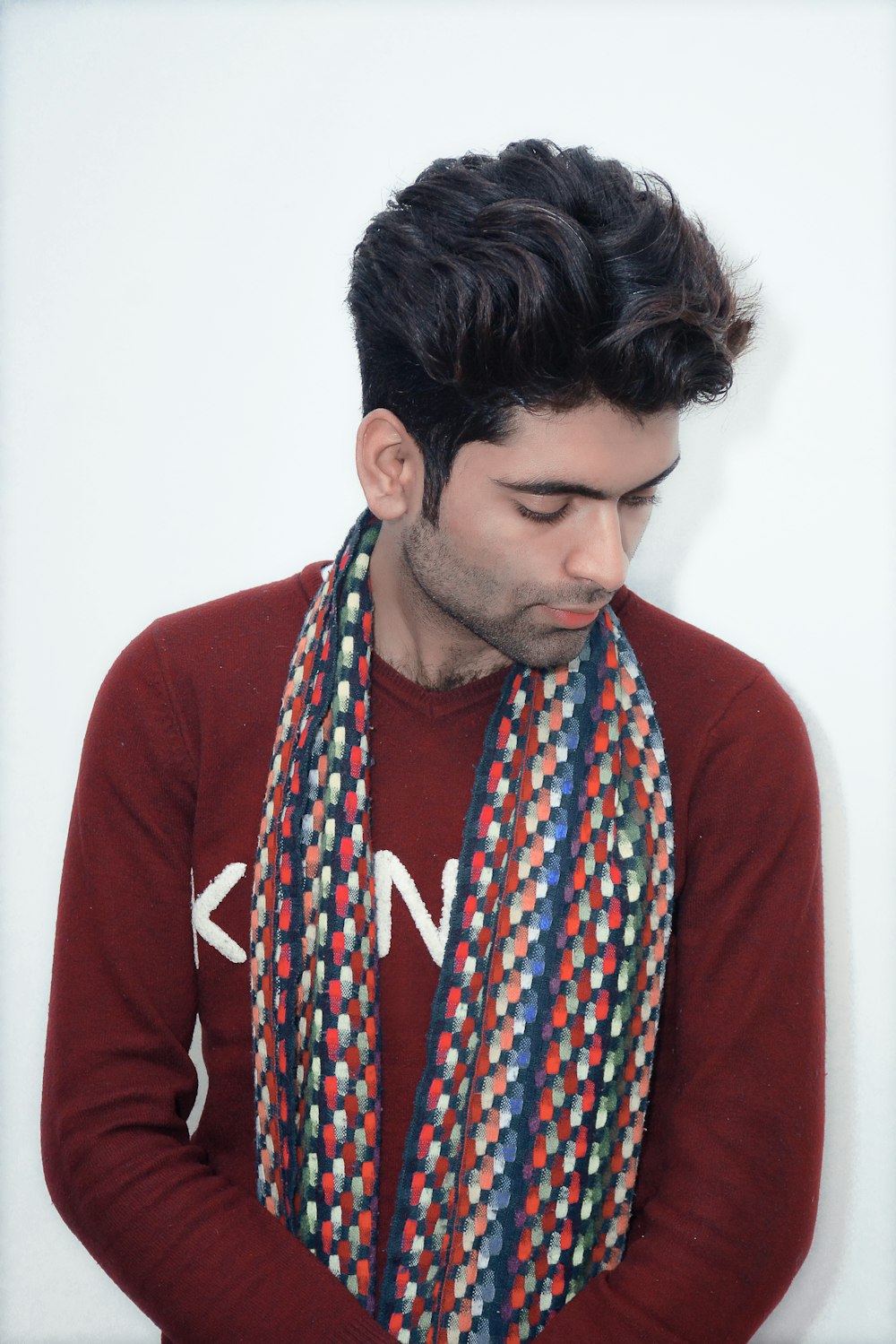 a man wearing a red sweater and a multicolored scarf