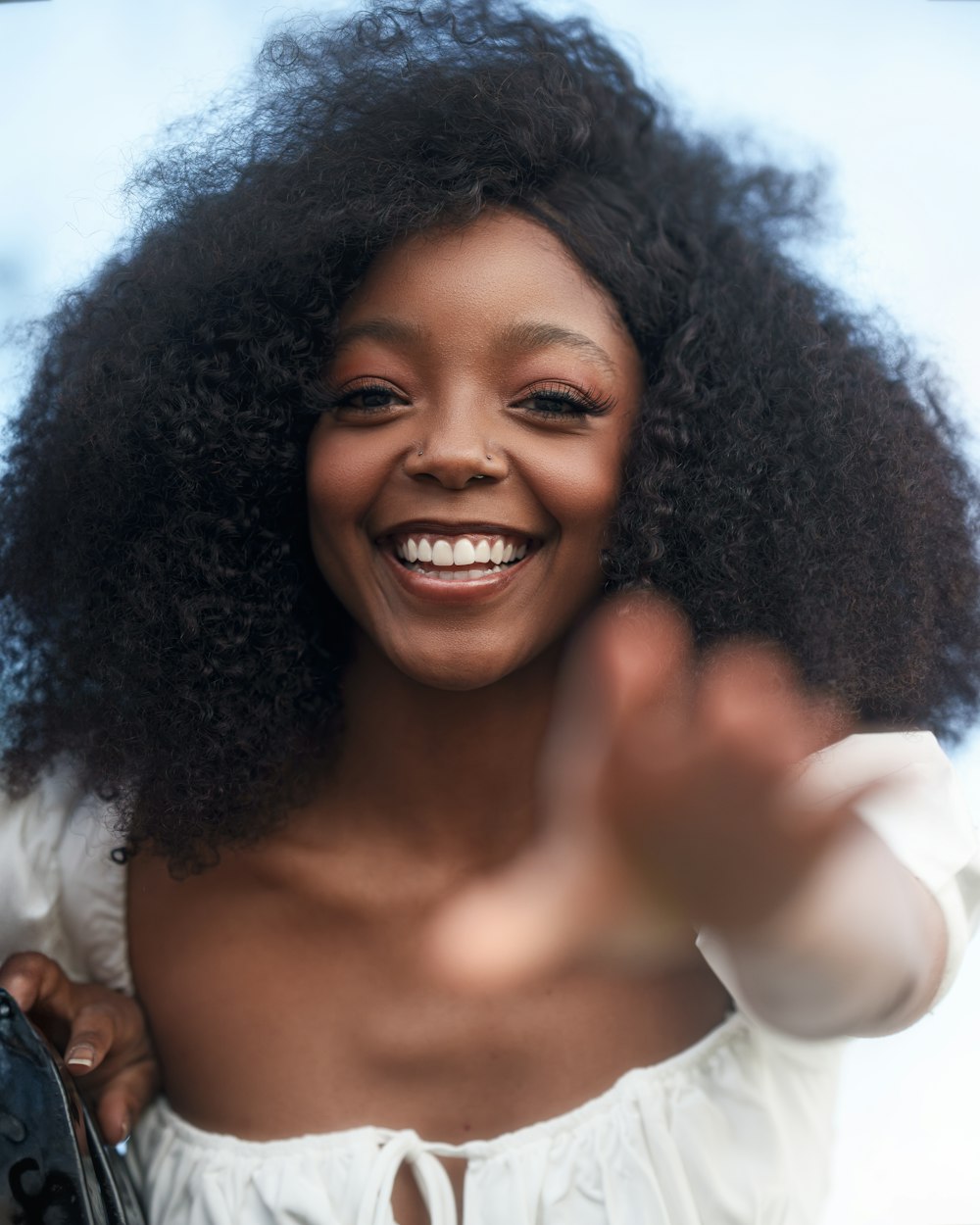 a woman with an afro smiles and waves