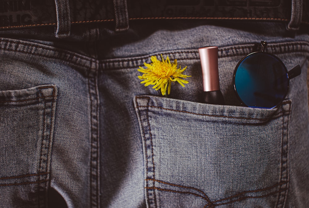 a yellow flower sticking out of the back pocket of a pair of jeans