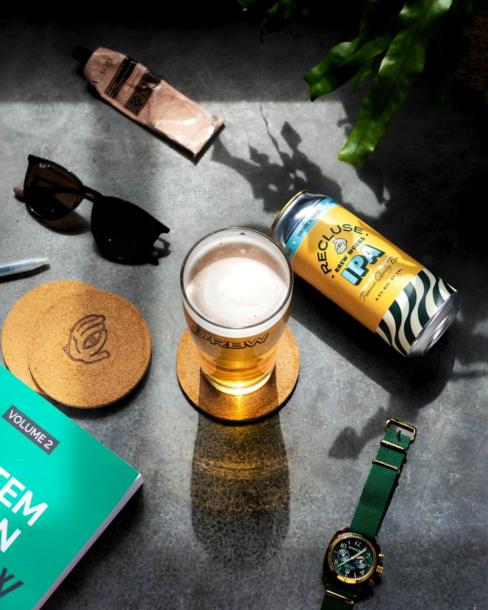 a glass of beer next to a book and a watch