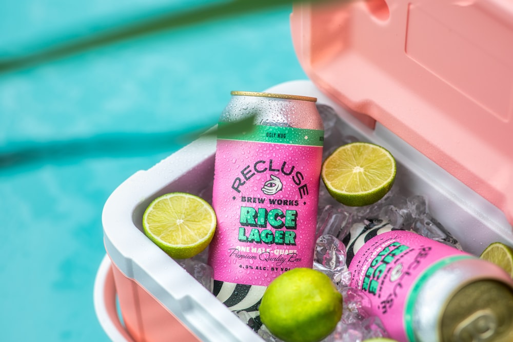 a pink cooler with limes and lemonade in it