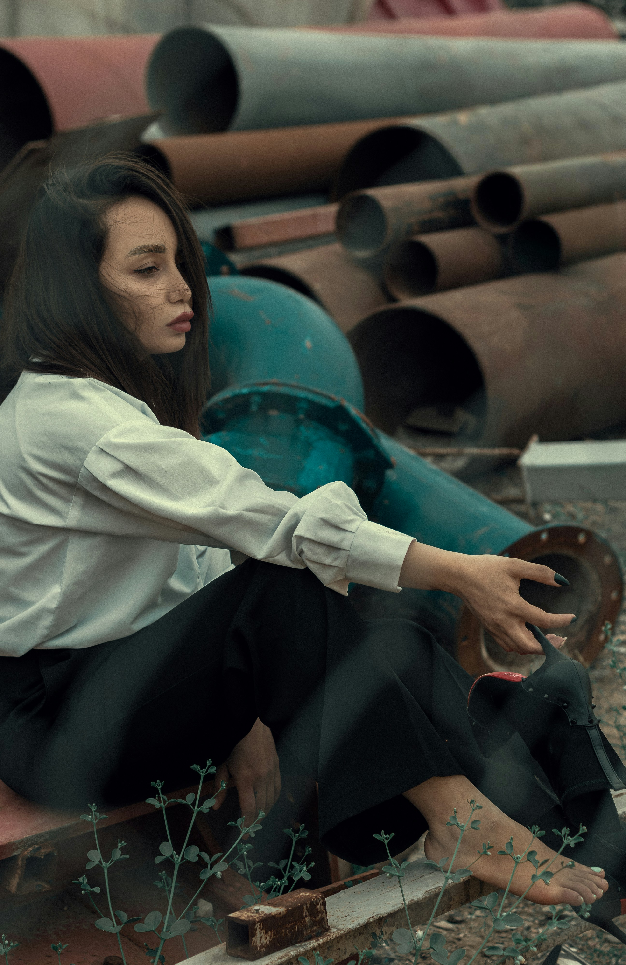 a woman is sitting on a pile of pipes