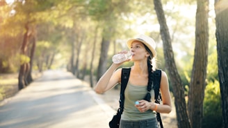 a woman in a hat drinking water from a bottle
