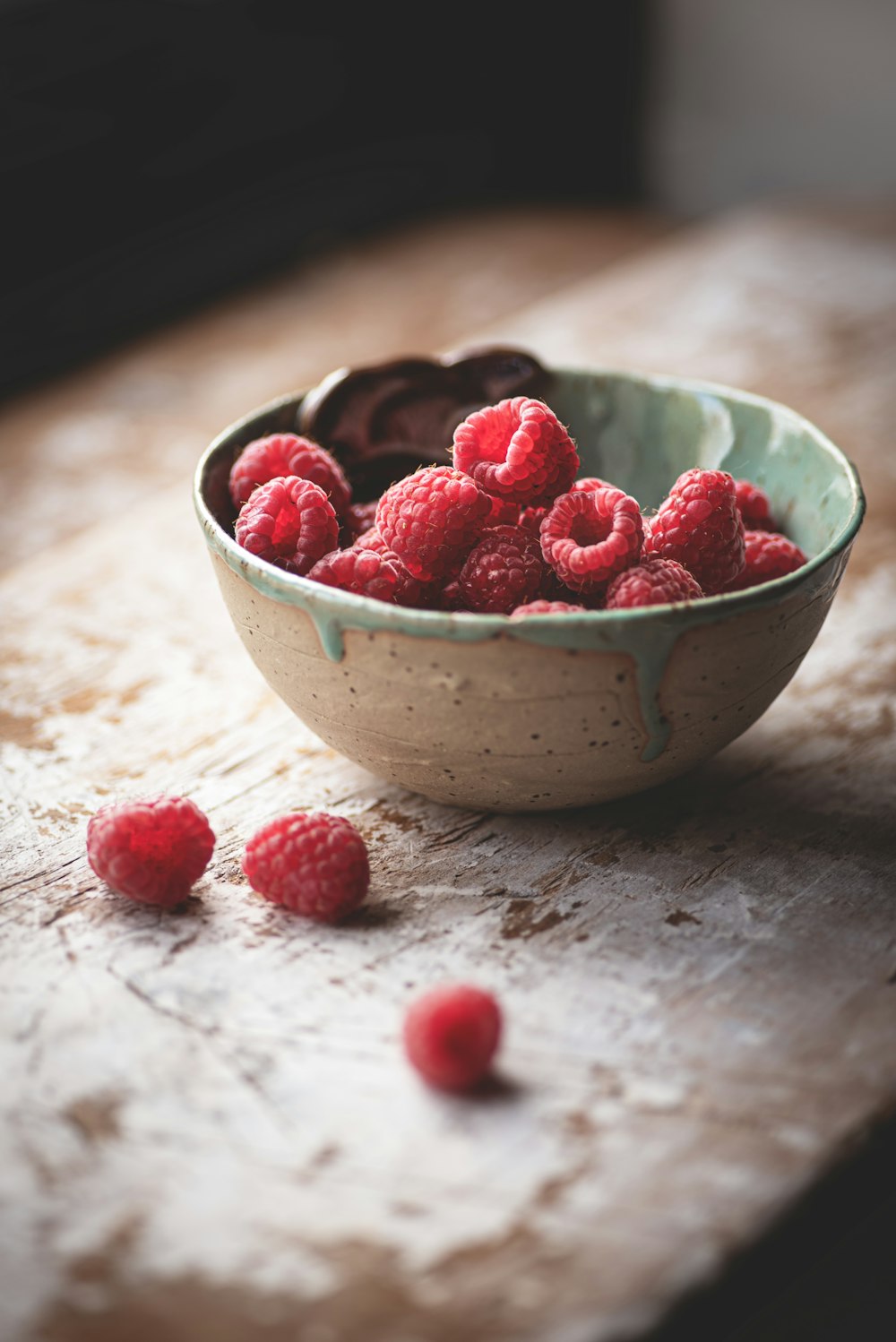 a bowl of raspberries on a wooden table