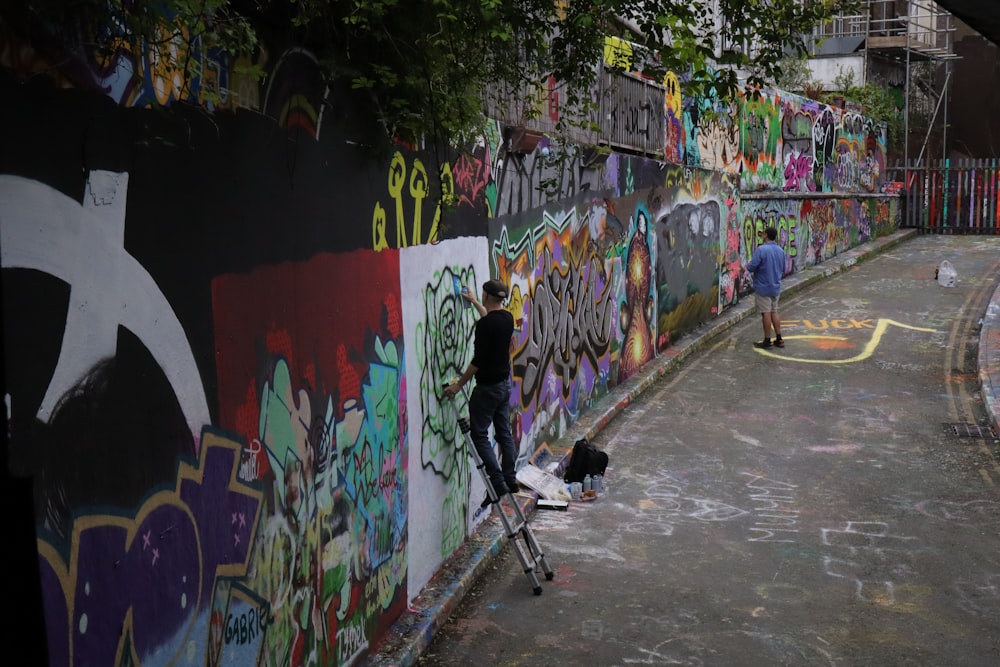 a man on a scooter painting a wall with graffiti