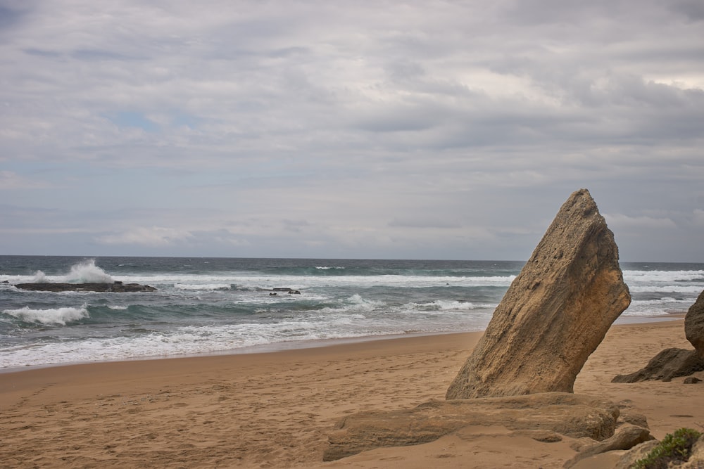 a large rock sitting on top of a sandy beach