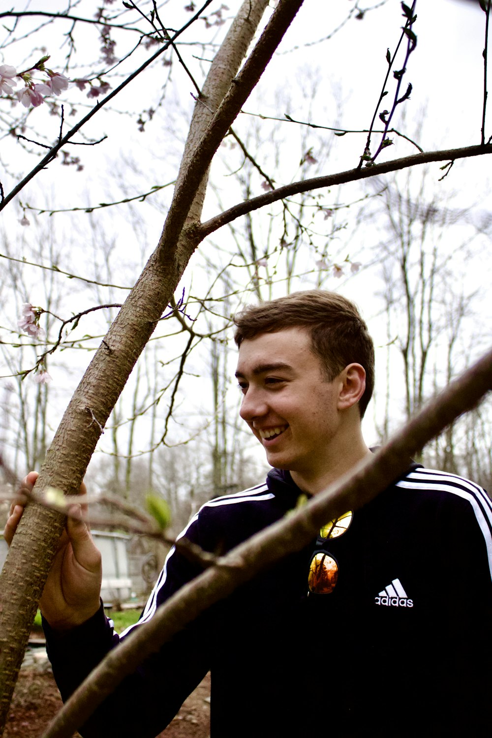 a man standing next to a tree holding a frisbee