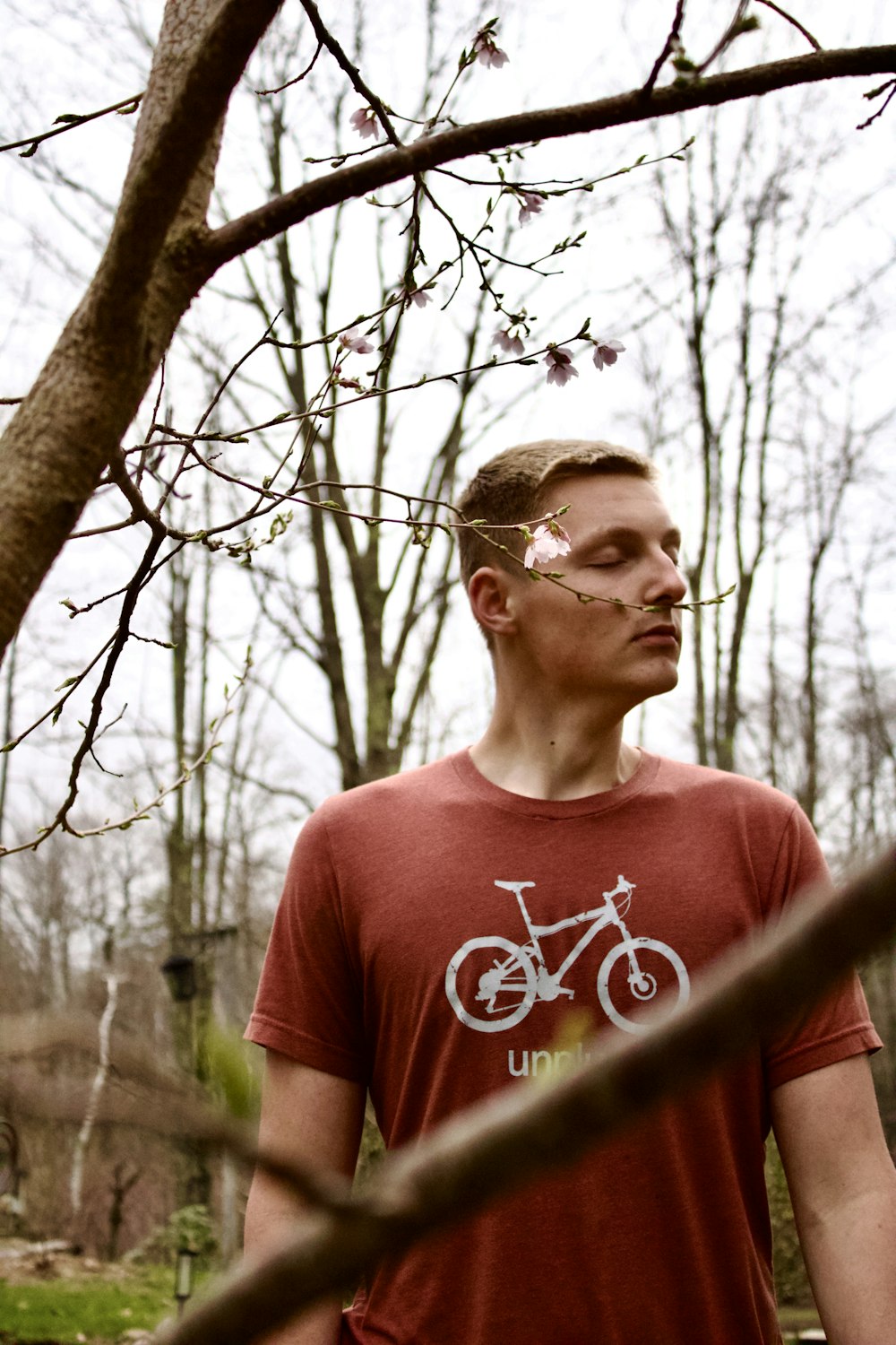 a man standing in front of a tree with a bicycle on it