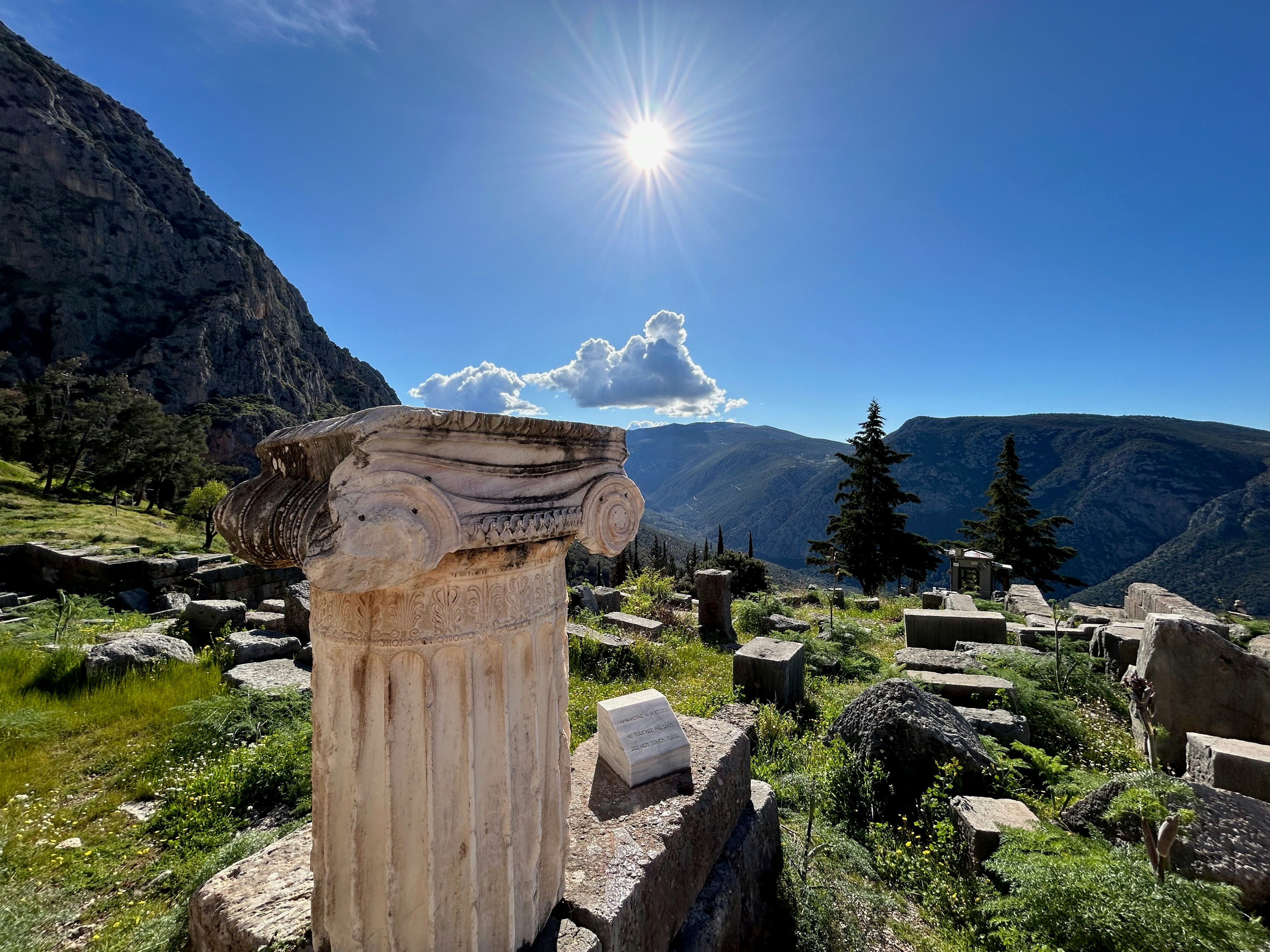 a stone pillar sitting on top of a lush green hillside, During trip to Greece in March of 2024 for being a total amateur, this was my favorite shot of the trip. We were marching up the path at the ruins of Delphi and captured this moment.