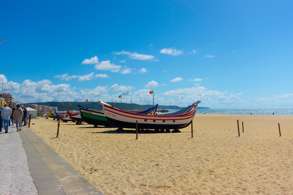 a row of boats sitting on top of a sandy beach