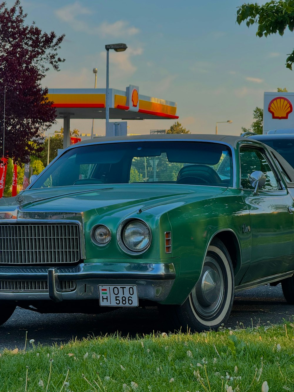 a green car parked in front of a gas station