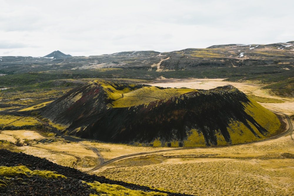 a mountain covered in green grass and dirt