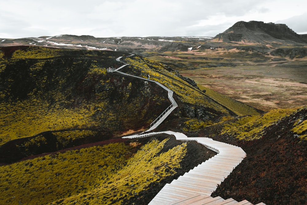 a wooden walkway going up a hill with a mountain in the background