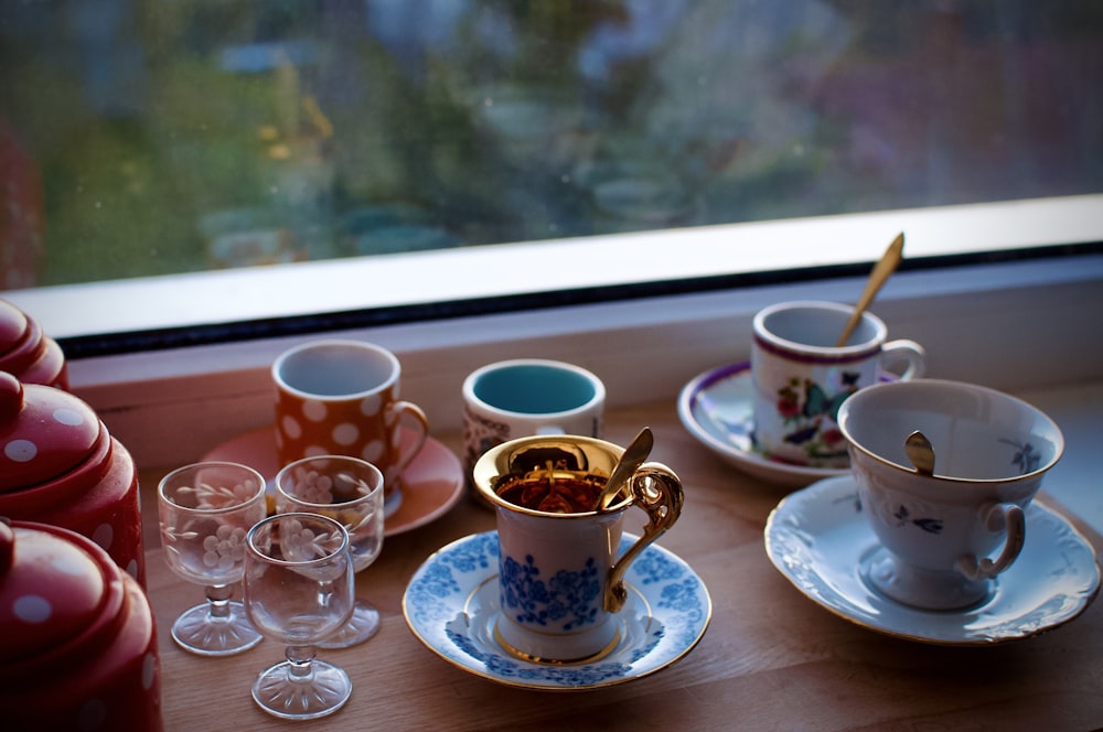 a table topped with cups and saucers next to a window