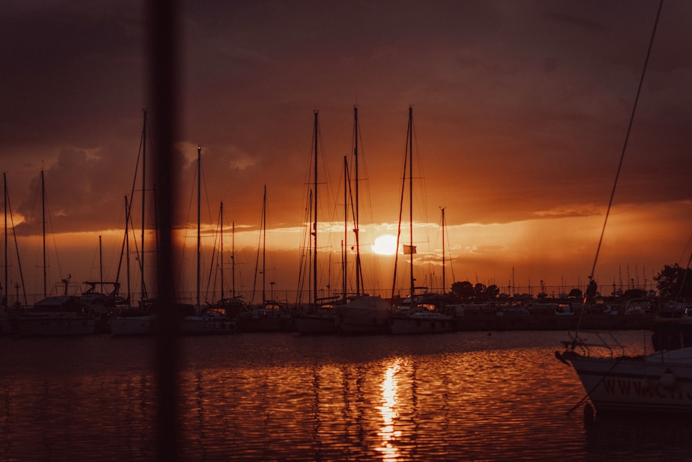 the sun is setting over a harbor with sailboats