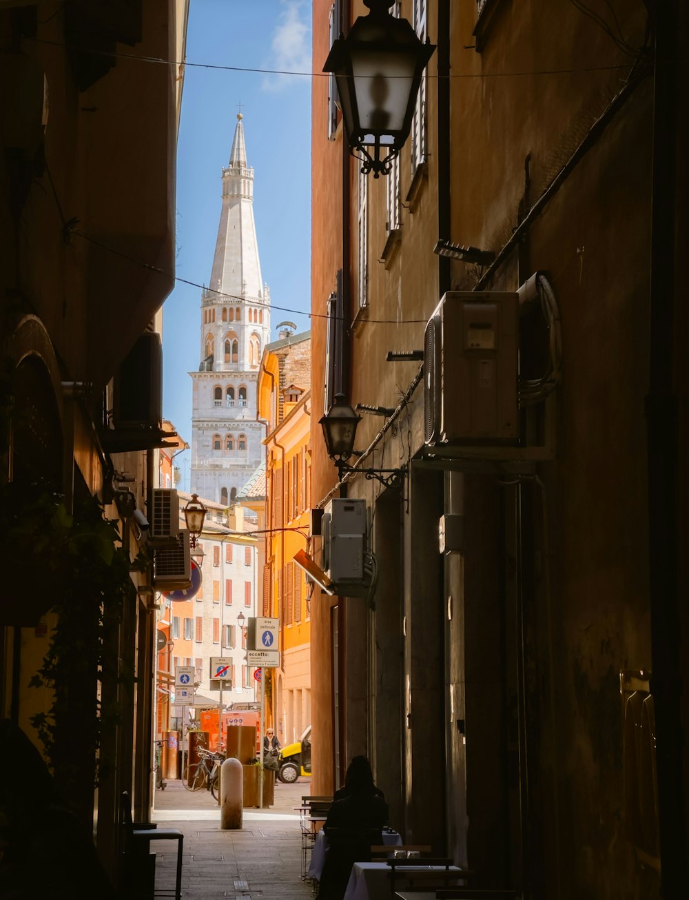 a narrow city street with a church steeple in the background