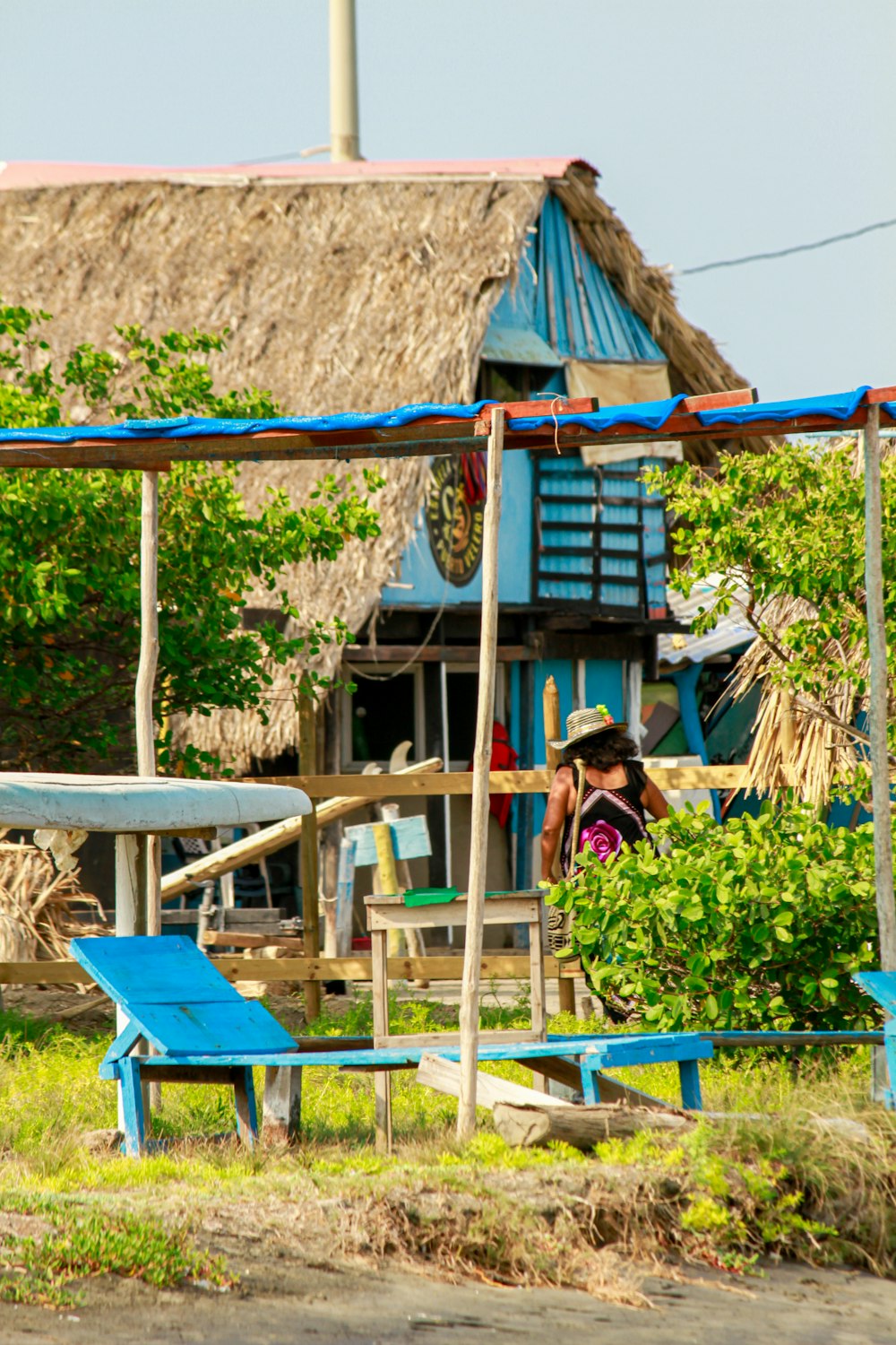 a woman is standing in front of a hut with a thatched roof