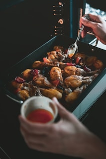 a person is spooning something into a pan of food