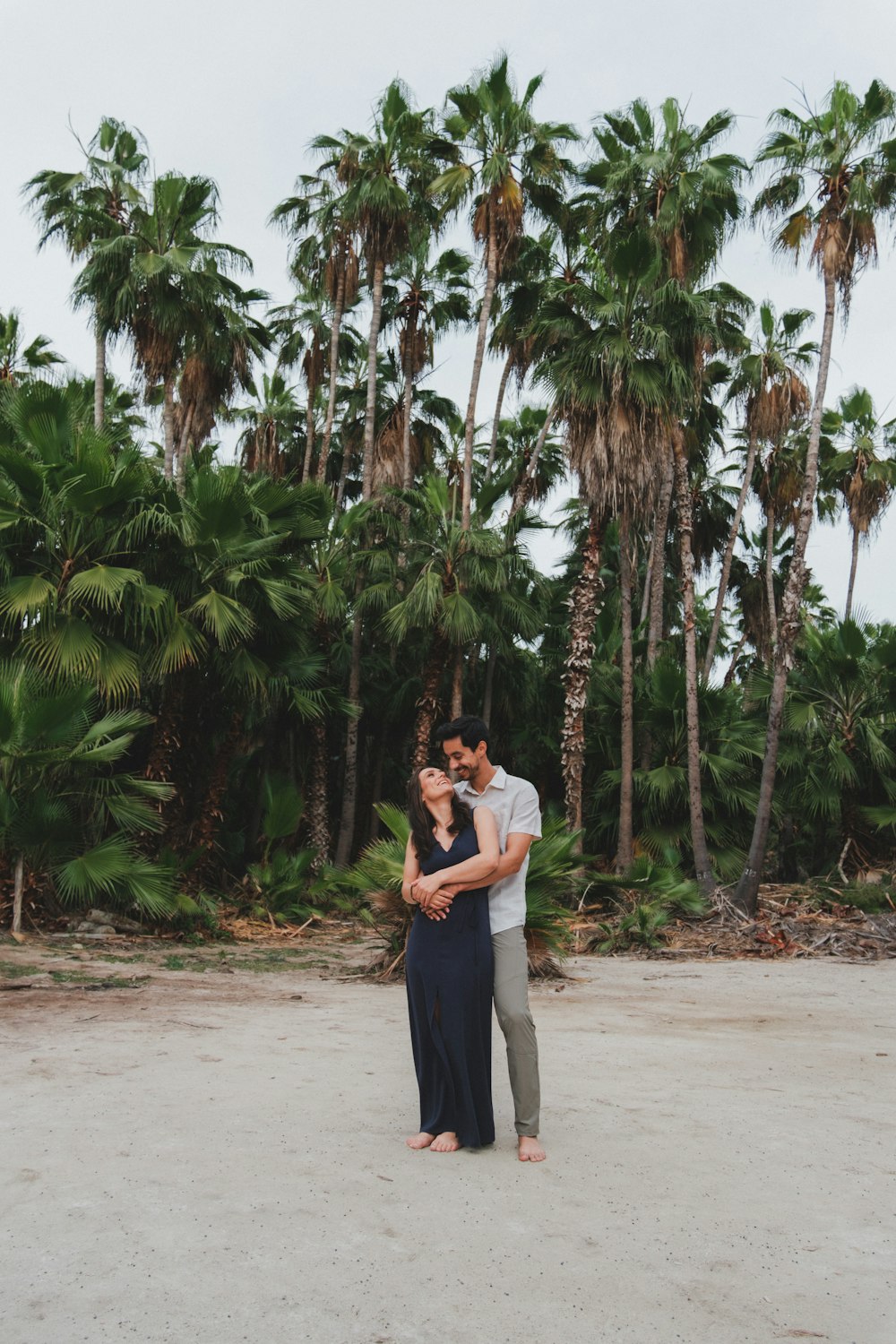 a man and woman standing in front of palm trees