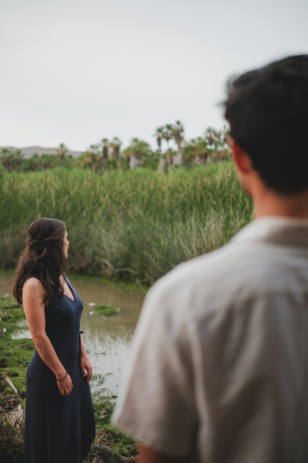 a man and a woman standing in front of a body of water